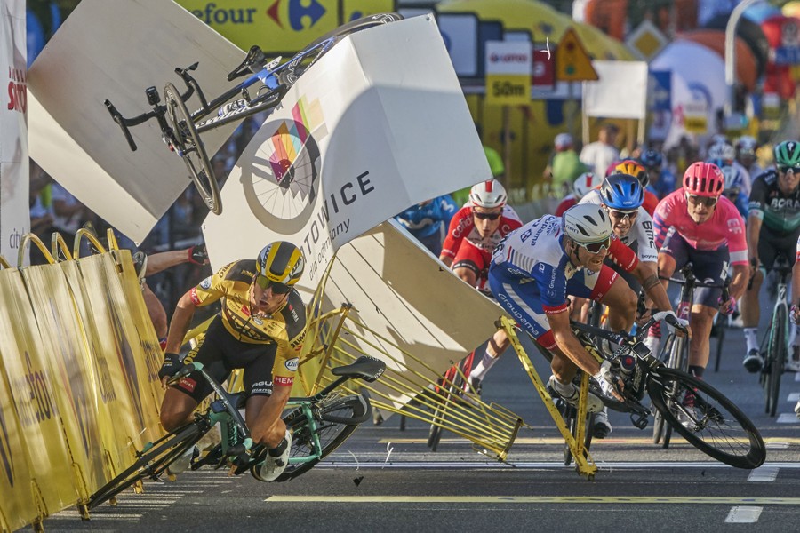 Several cyclists crash along temporary fencing near the finish line.