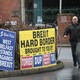 A man walks past posters reading "Brexit Hard Border Brought to You By Tories, DUP" and "West Belfast Stands Against Brexit."