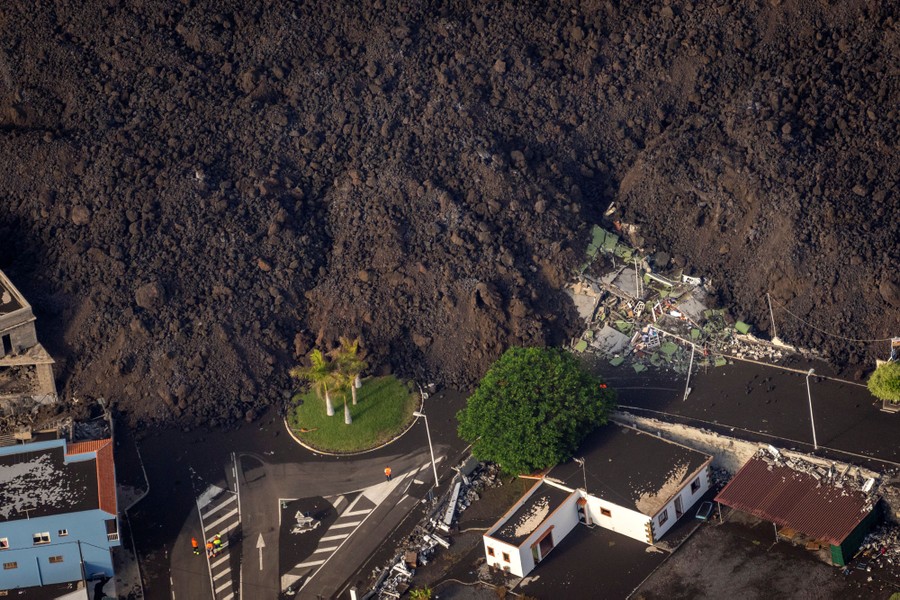 Piles of volcanic rock, part of a lava flow, sit among houses and streets.