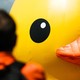 A person looks at the face of a giant inflatable rubber duck.