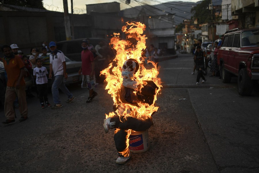 A seated effigy burns on a city street.