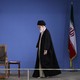 Ali Khamenei walking next to an empty chair