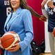 A photograph of Kamala Harris holding a basketball, with members of the American Olympic men's basketball team seen in the background