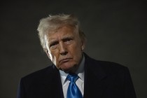 Donald Trump looks at the camera in front of a dark sky