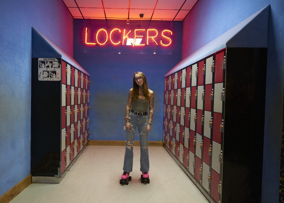 a woman on skates in front of a neon sign and lockers
