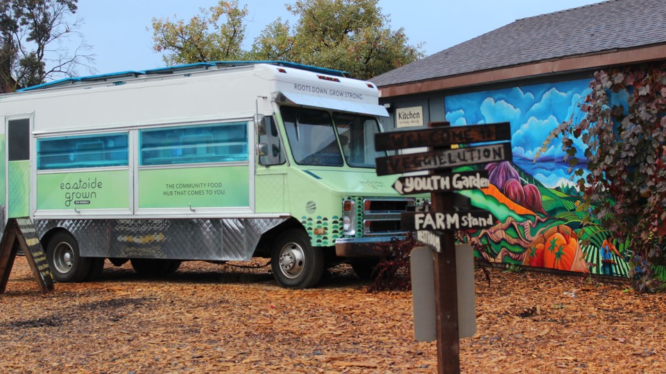 A green and blue food truck parked outside a colorful building