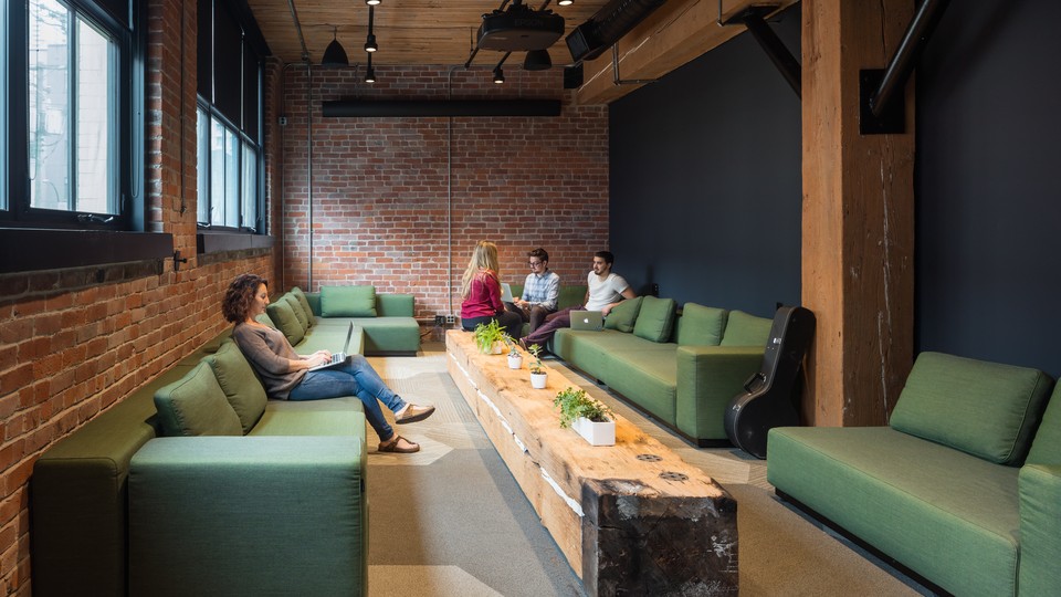 Several people sitting on green couches with laptops