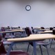 An empty classroom with desks and a clock on the wall