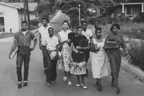 Jo Ann Allen Boyce and nine other Black students walk together down an empty road on their first day of desegregating Clinton High School in Clinton, Tennessee.