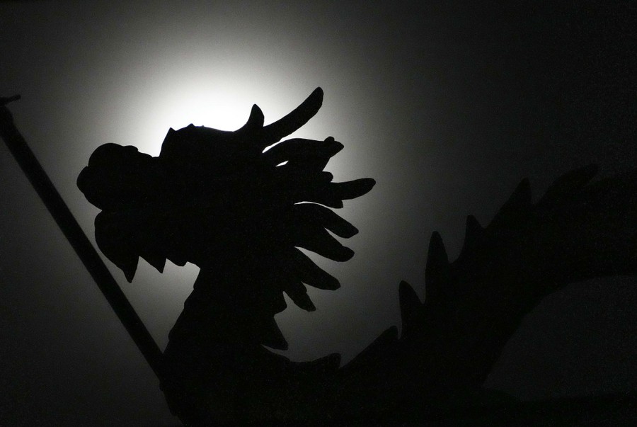 Moonlight shines behind a dragon statue.