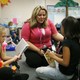 A substitute teacher sits on the floor with students as they read.