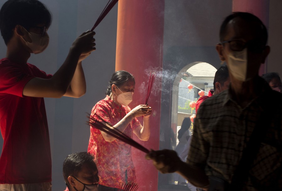 Several people say prayers while holding burning incense.
