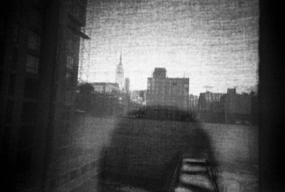 Shadow figure looking over black and white city scene