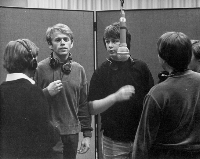 a black and white photo of The Beach Boys recording music in the studio