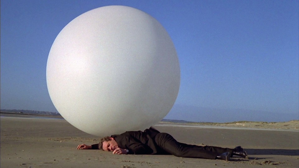 A man lays on the ground in front of a big white ball