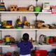 A kid stands in front of shelves of toys