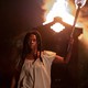 A woman holding a torch in front of a burning building