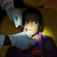 A dentist examines the inside of a young boy's mouth.