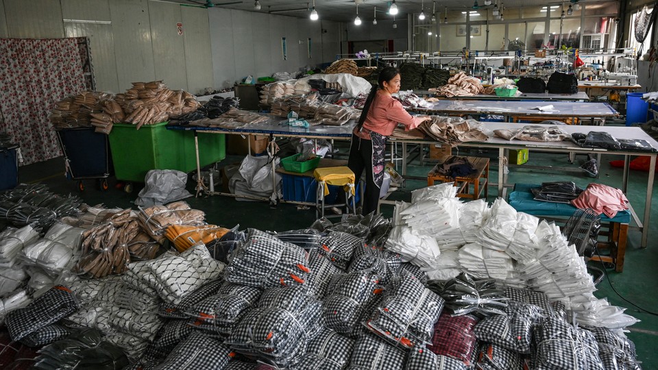 a woman works in a warehouse with clothes piled up