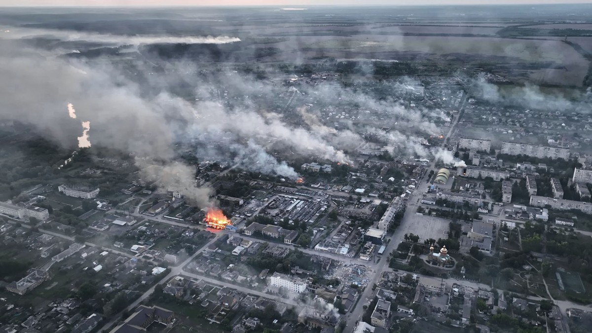 An aerial view of city buildings and houses, showing many fires burning across a wide area