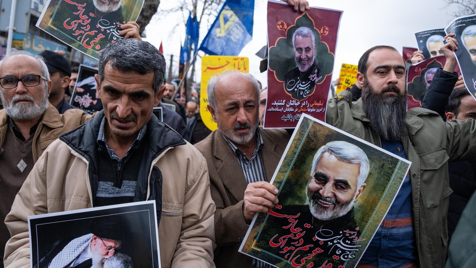Protesters holding posters of Qassem Suleimani