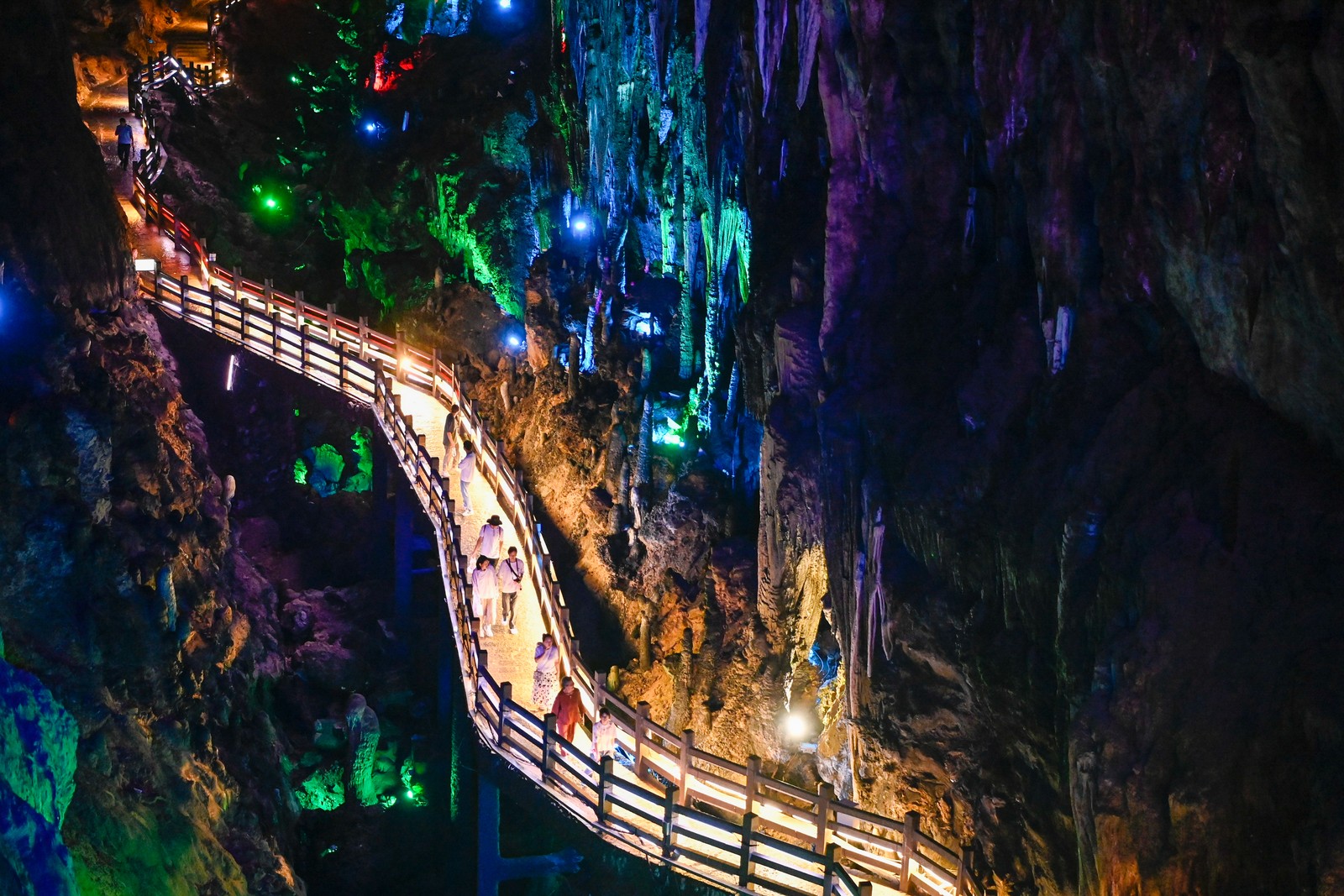 The interior of a tourist-friendly cave, colorfully lit, with a raised walkway.