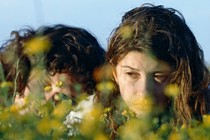 Two young girls embrace in a grassy field