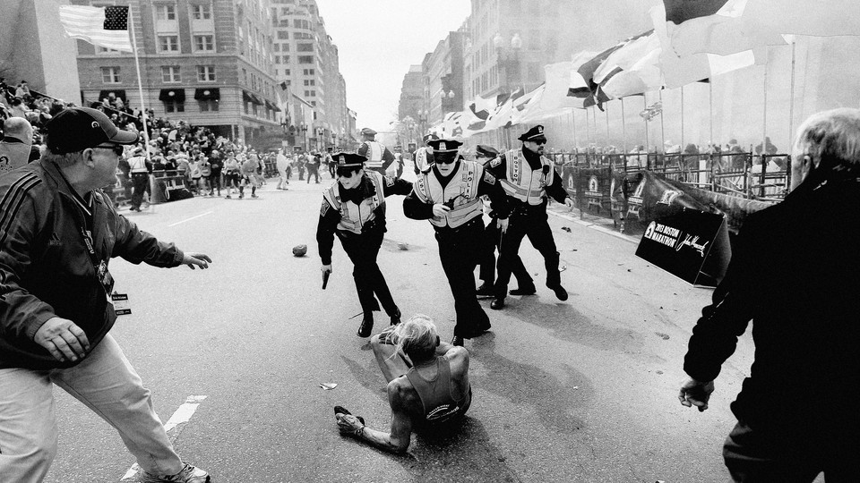 Picture showing police assisting a marathon runner on the ground, a cloud of smoke, and people running in the background