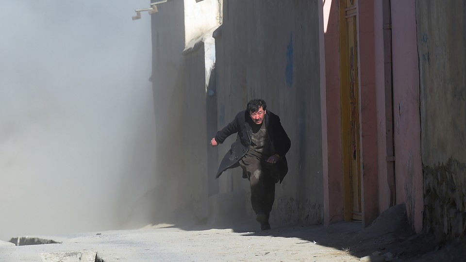 A man runs from dust that followed an attack on a Shiite cultural center in Kabul in 2017.