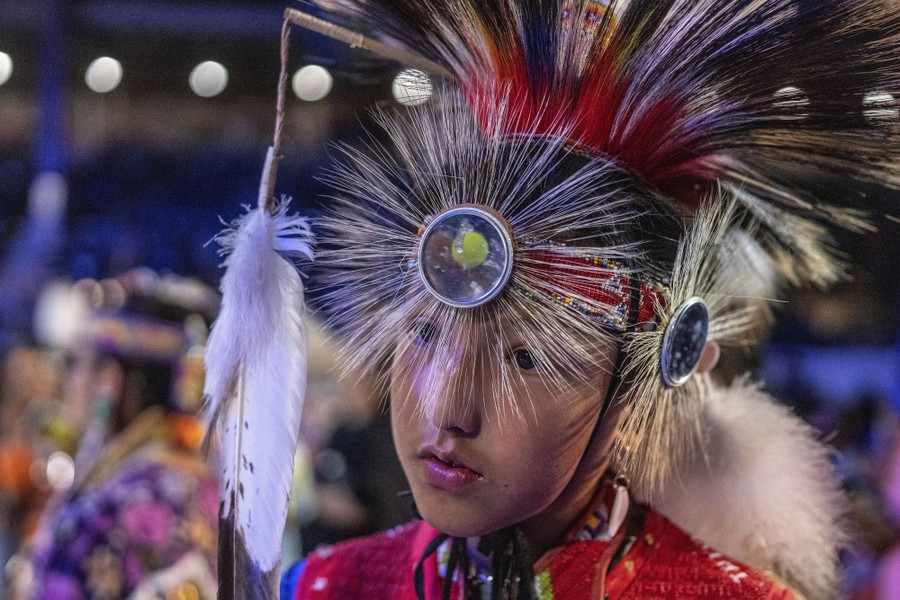 A boy wears traditional feathered head gear.