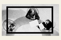 An illustration of two corporate workers sitting at a desk looking at papers