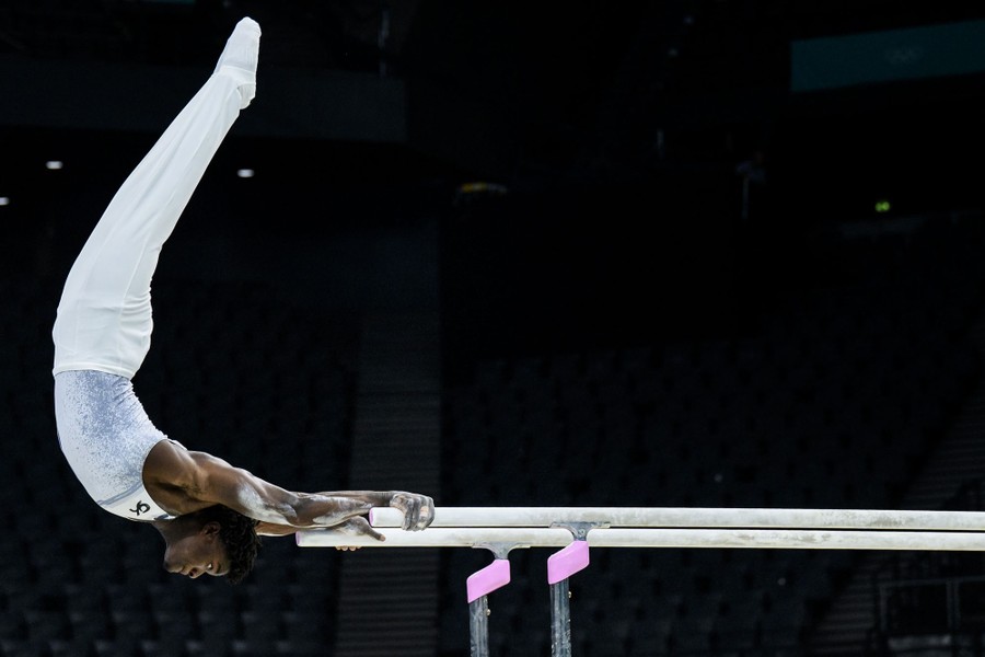 A gymnast swings from the ends of a set of parallel bars.