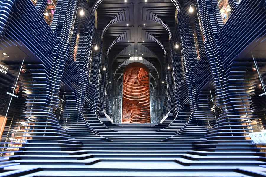 An interior view of a modern, elaborately designed two-story staircase and open space inside a bookstore