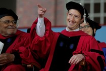 The Facebook founder Mark Zuckerberg points and smiles while wearing a cap at gown at Harvard's commencement