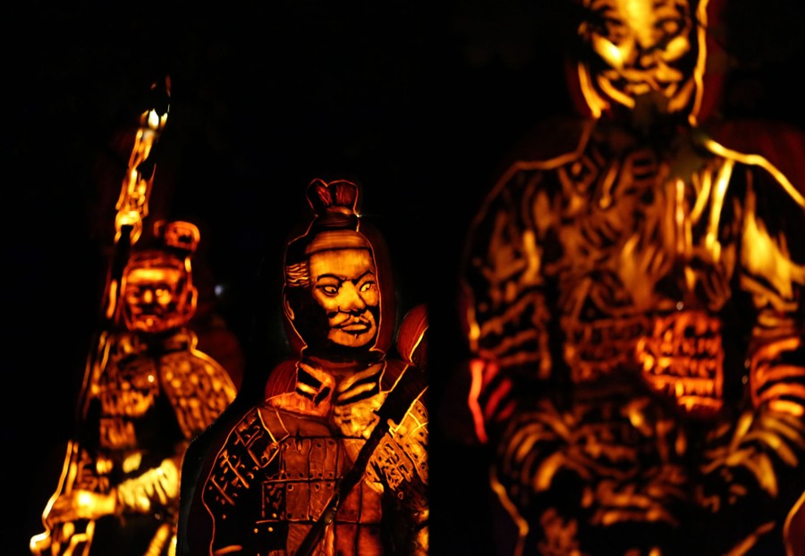 Stacked and illuminated pumpkins, carved to resemble ancient warriors