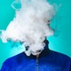 A person's face is obscured by a cloud of vapor.