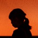 A silhouette of a woman against an orange textured background