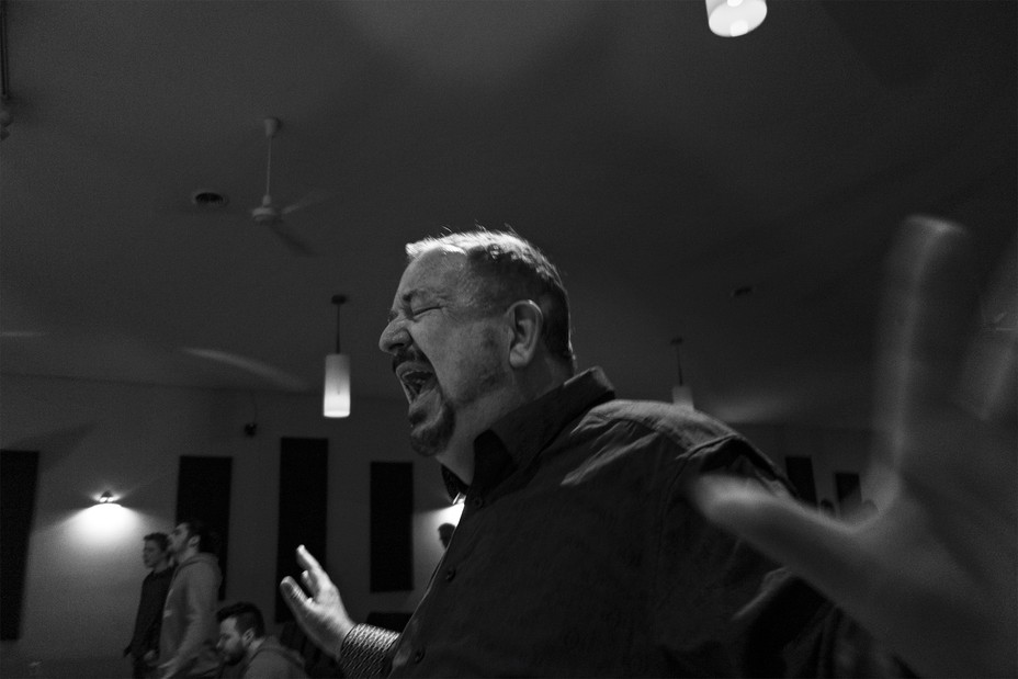 photo of man with eyes closed, shouting, with arms spread wide