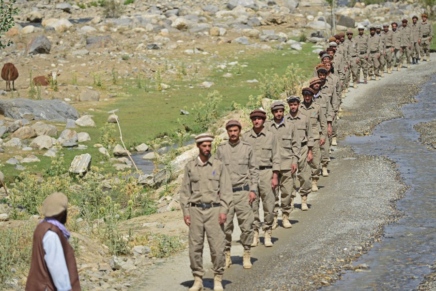 A line of soldiers stands alongside a dirt road.
