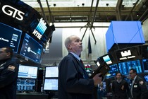 A trader looking up at screens on the stock exchange floor