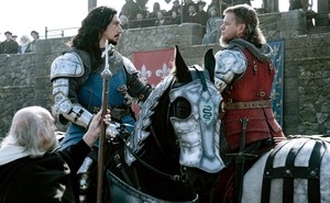 Adam Driver and Matt Damon are seen in armor, on horseback, staring each other down