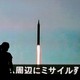 People walk in front of a monitor showing news of North Korea's fresh threat in Tokyo