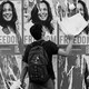 A black-and-white photo of a man tearing down a poster among a spread of identical posters depicting Kamala Harris and the word 'freedom.'