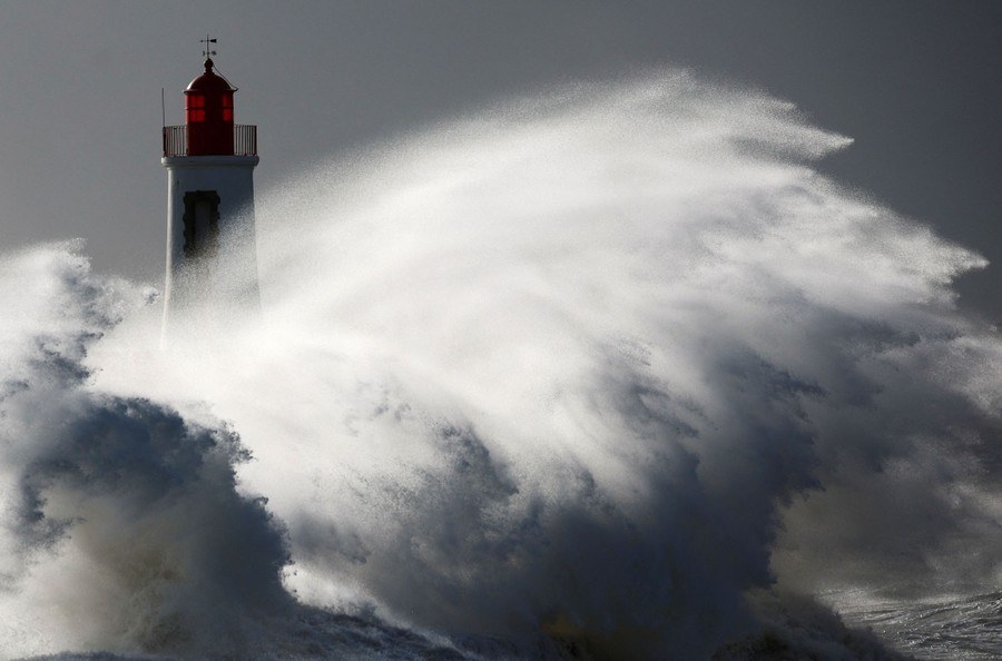Waves crash against a lighthouse during a storm.