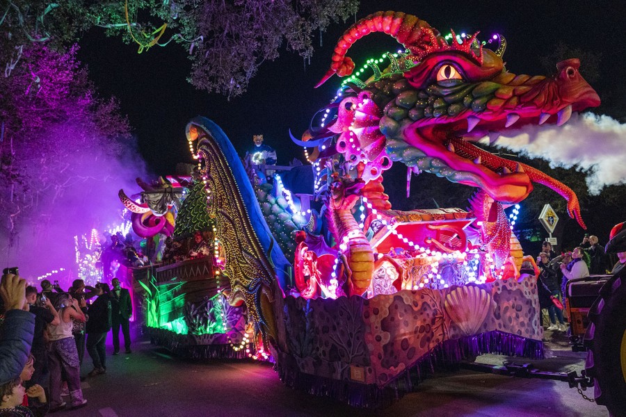 A large and colorful float sculpted into the shape of a dragon moves along in a parade during Mardi Gras activities.