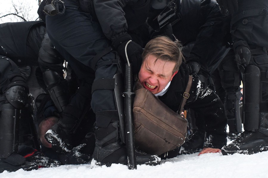 A man makes a pained face as several police officers hold him down.
