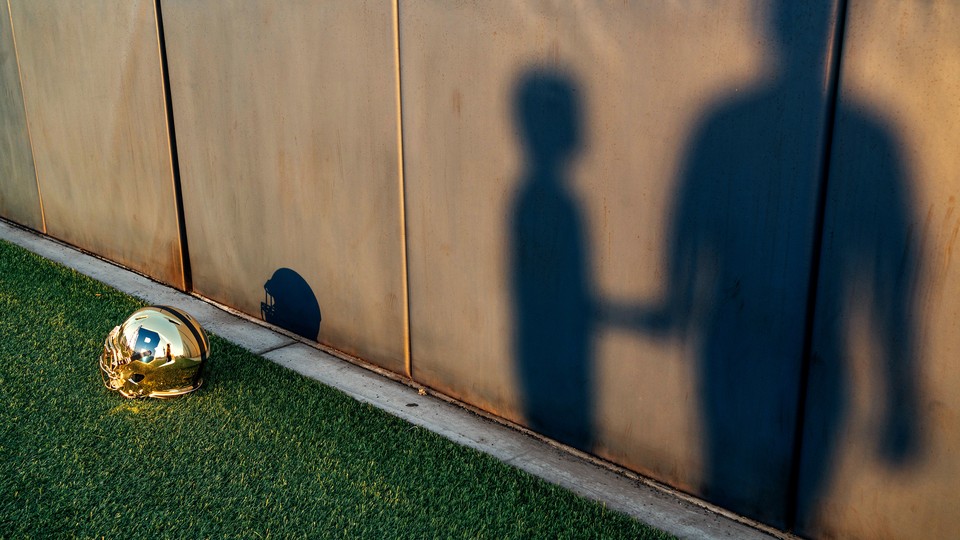 A football helmet next to the shadows of a child and an adult.