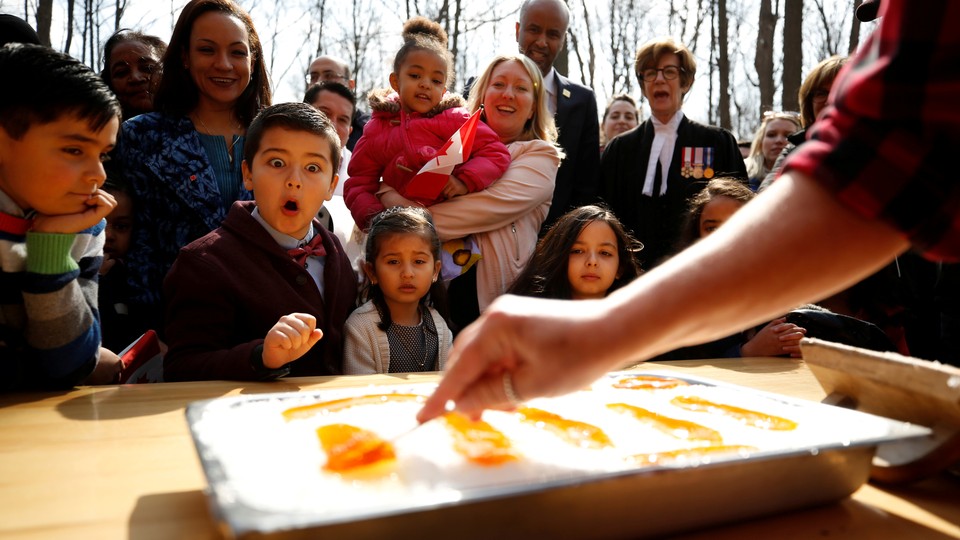 New Canadian citizens react as maple taffy is prepared following a citizenship ceremony in 2018