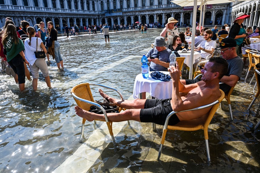 People sit and walk through ankle-deep floodwater in Venice's St. Mark's Square.