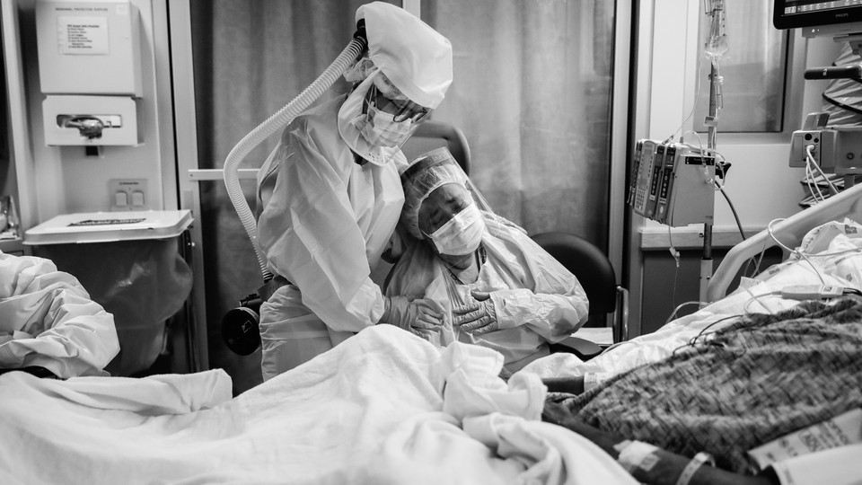 Romelia Navarro is comforted by Michele Younkin, a nurse, while sitting at the bedside of her dying husband.
